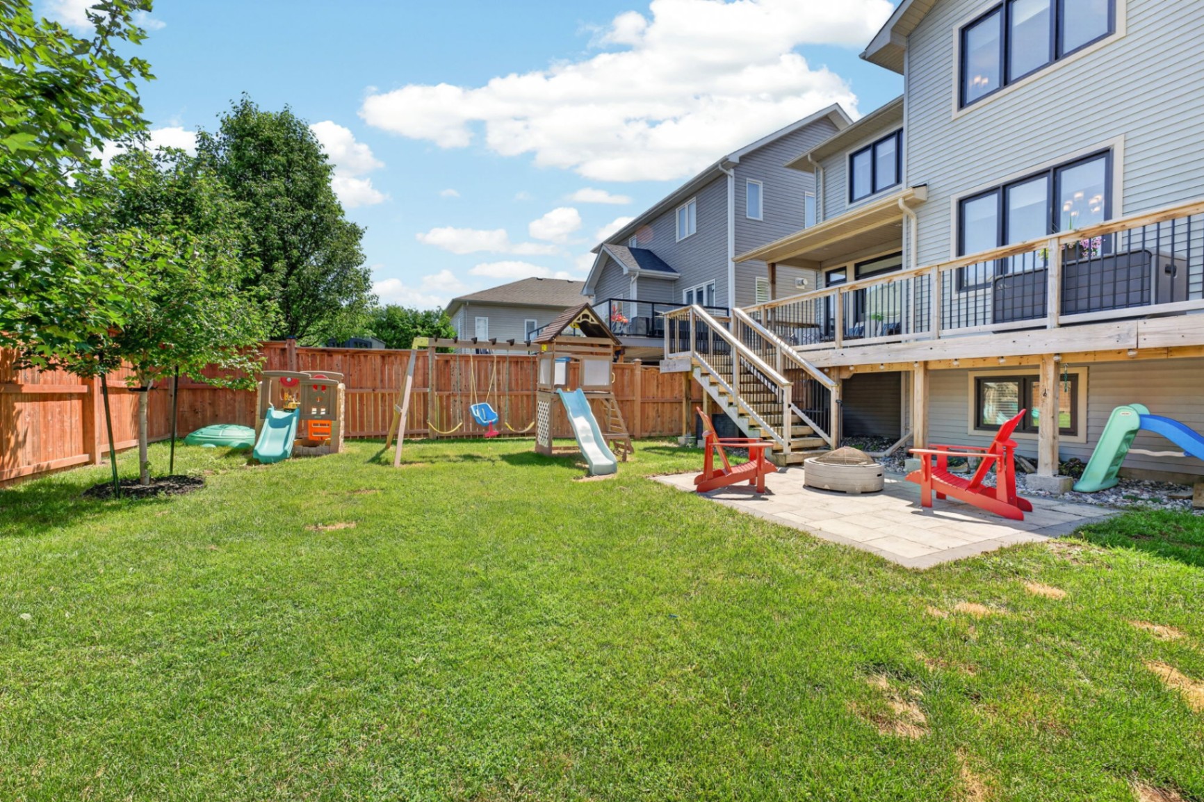 Fully fenced backyard with patio, fire pit, and playset